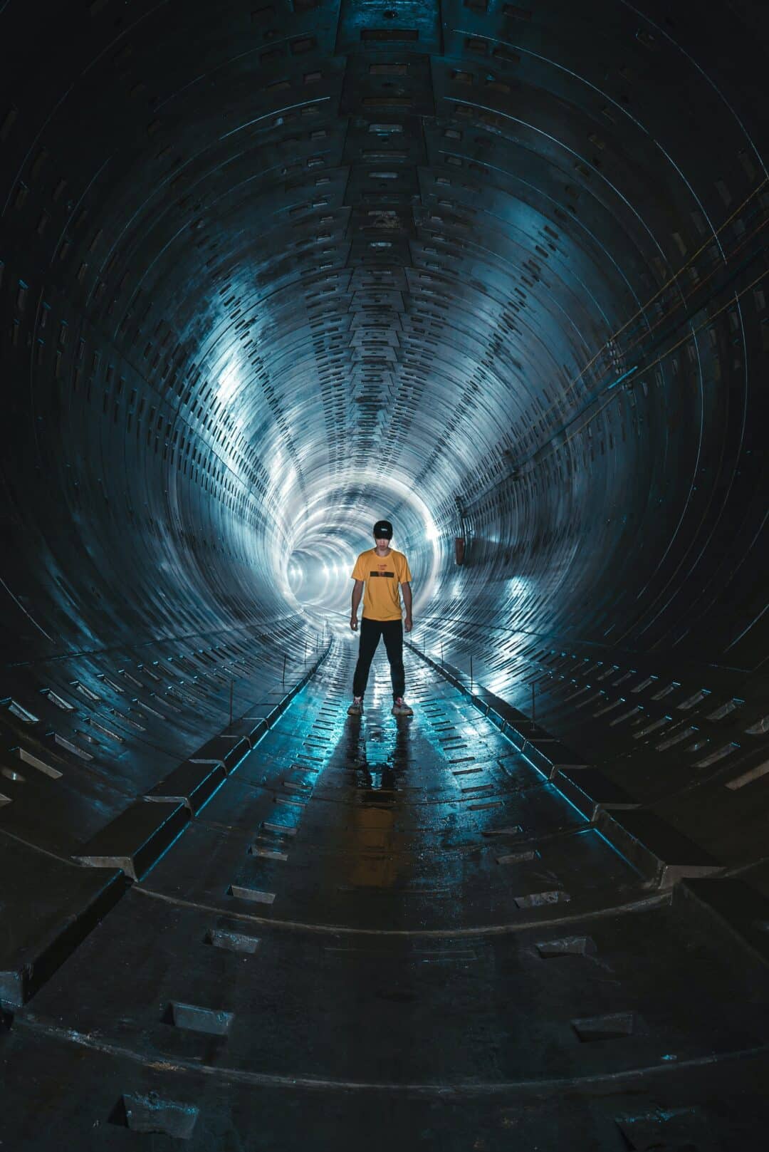 A man in a yellow t-shirt is standing in a tunnel. En man med gul t-shirt står i en tunnel.