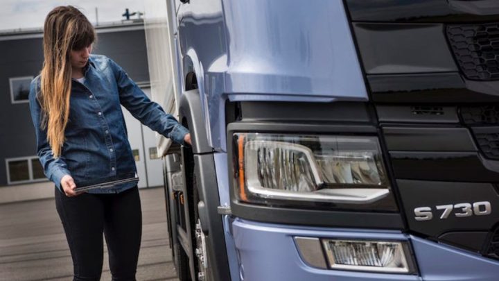 Woman with ipad checking a lorry. Kvinna med ipad kontrollerar en lastbil.