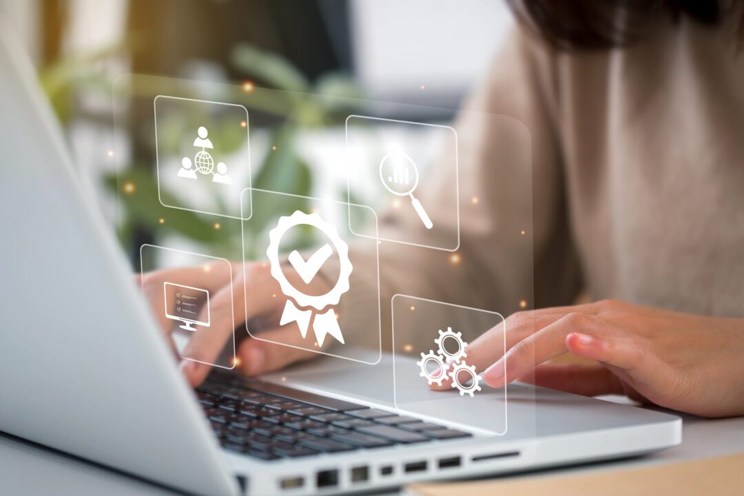 A woman at a laptop showing a quality control certification for licence management. En kvinna vid en laptop som visar en kvalitetskontrollcertifiering för licenshantering.
